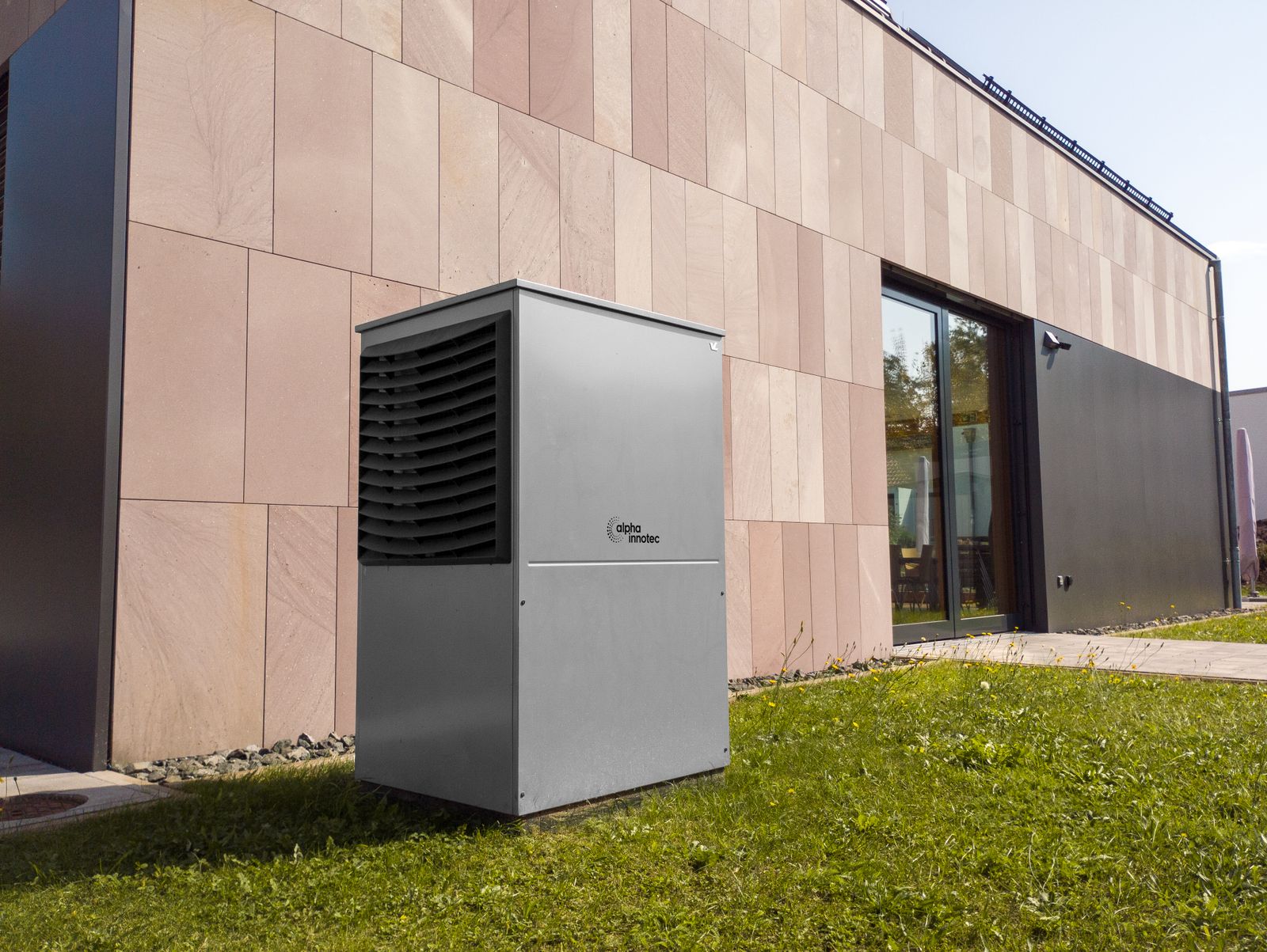 An outdoor heat pump on a gravel bed beside a white house wall